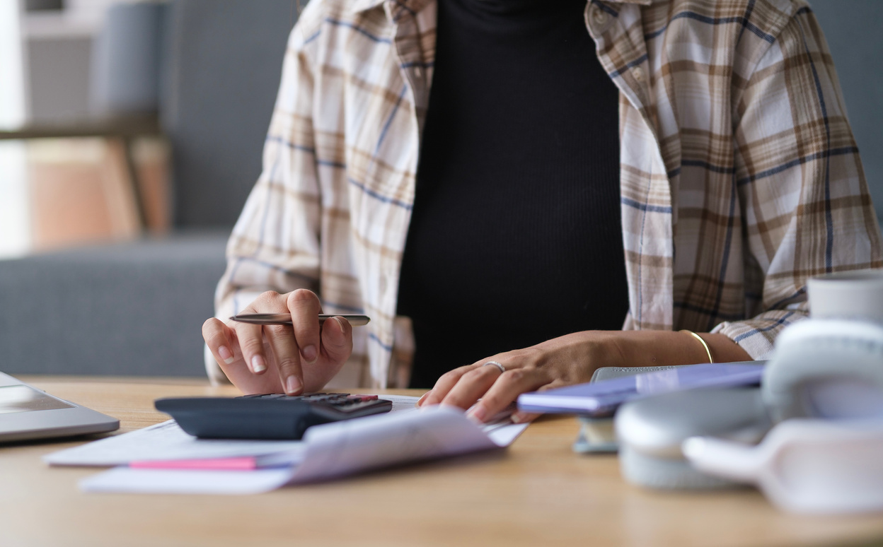 Woman using calculator, counting monthly budget, household expenses, rental fees, paying bills online.