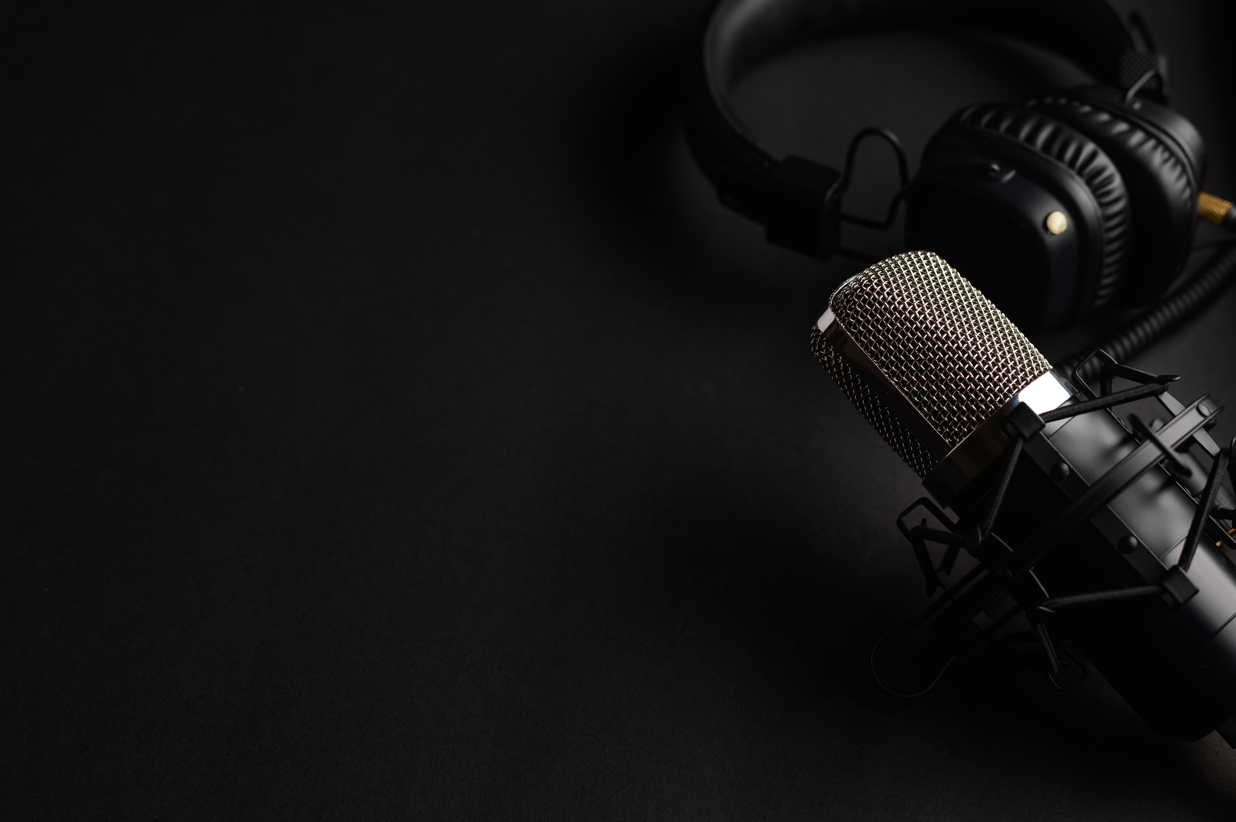 Studio black studio microphone with studio headphones on a black background. Banner. Radio, work with sound, podcasts.